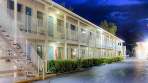 Un motel con varios pisos, escaleras exteriores e iluminación destacada en la fachada.