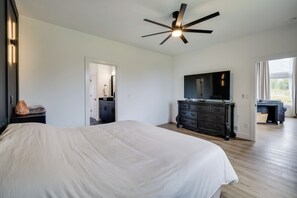 A bedroom with a large bed, a ceiling fan, a dresser, and a television. - Hatcher Pass Northern Lights Home (Palmer)