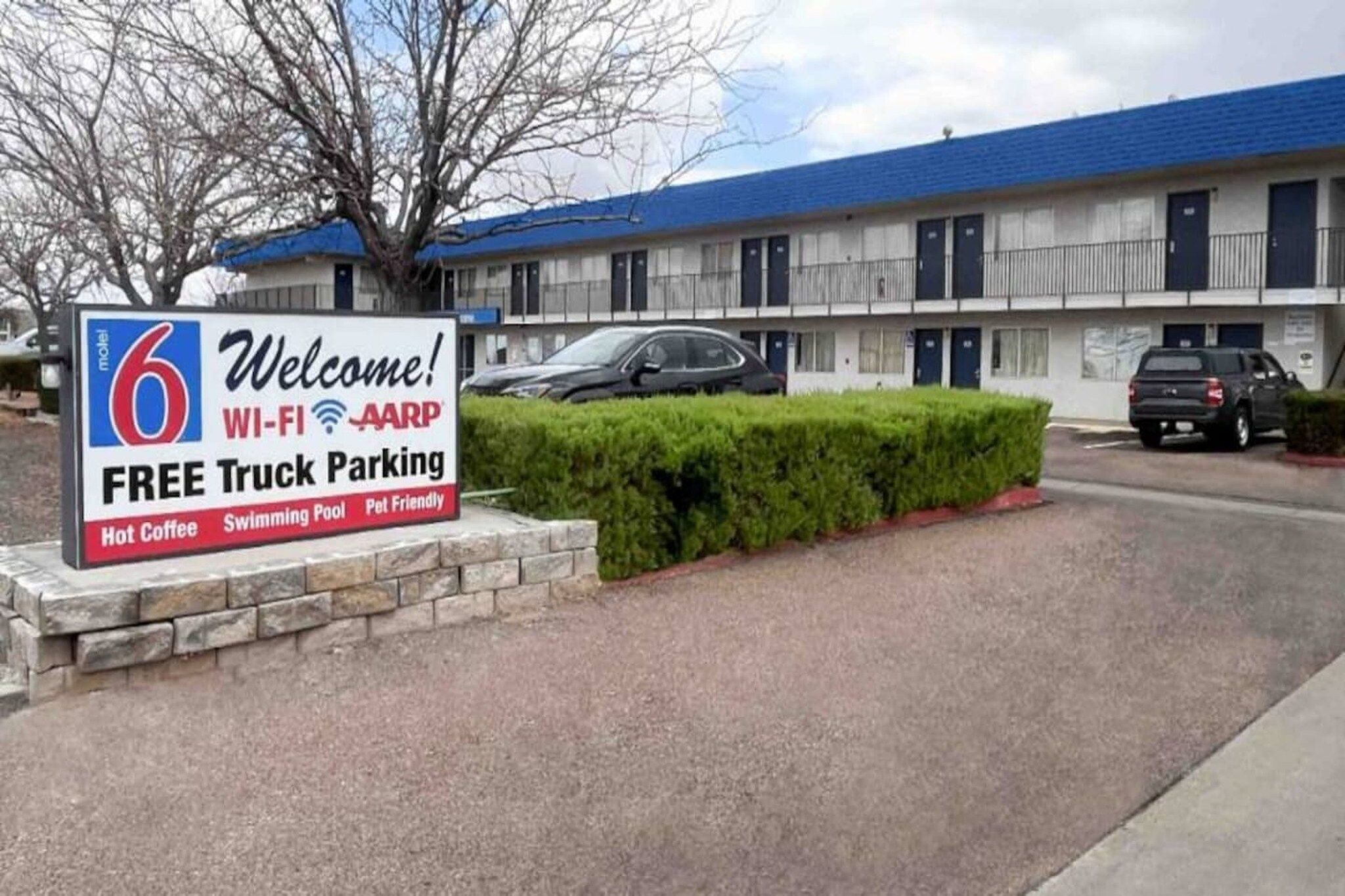 Un motel avec une enseigne indiquant qu’il offre un parking gratuit pour les camions, une connexion Wi-Fi, un programme d’adhésion à l’AARP, du café chaud, une piscine et des chambres acceptant les animaux de compagnie.