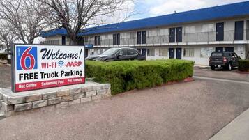 Un motel avec une enseigne indiquant qu’il offre un parking gratuit pour les camions, une connexion Wi-Fi, un programme d’adhésion à l’AARP, du café chaud, une piscine et des chambres acceptant les animaux de compagnie.