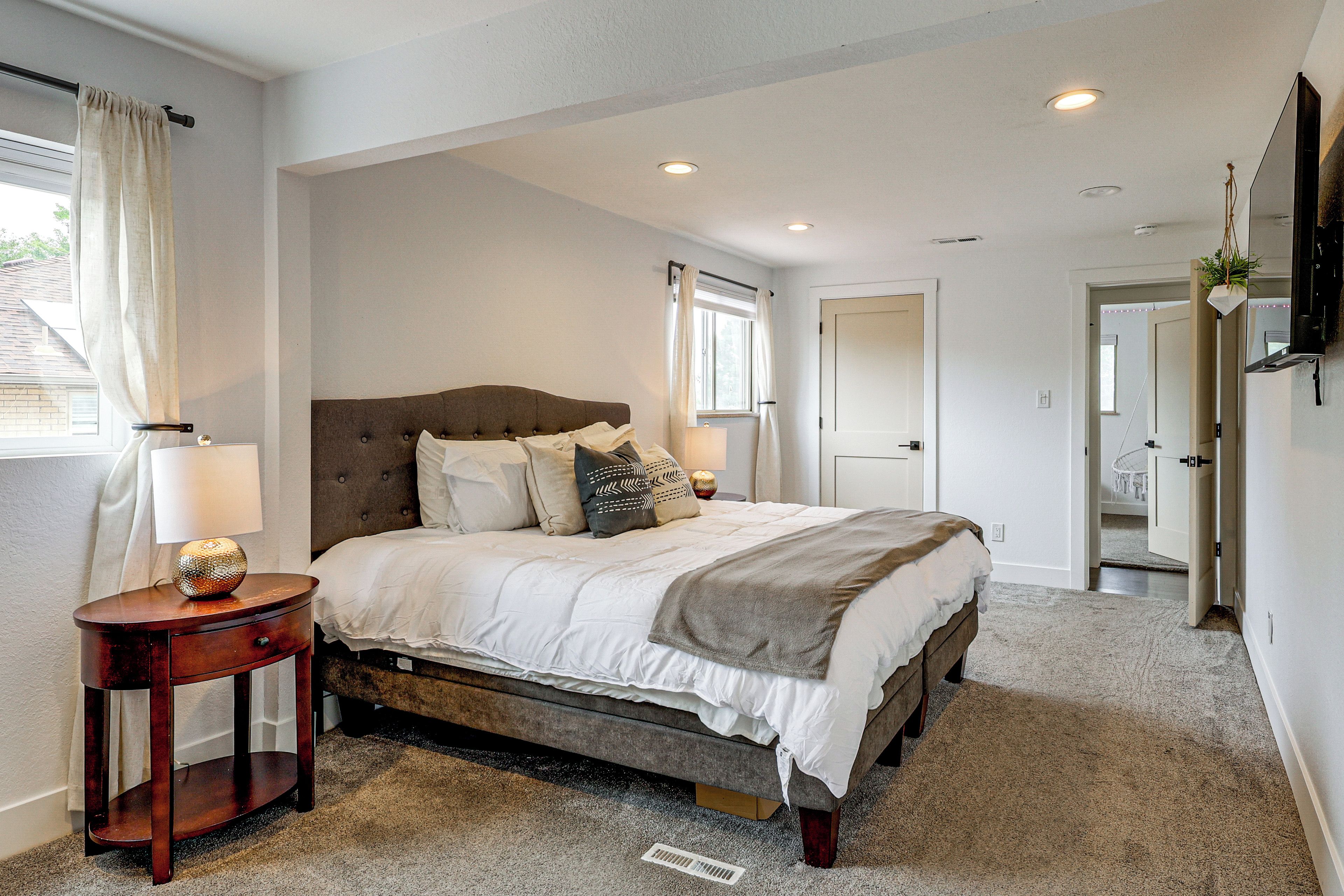 A bedroom with a bed, bedside table, lamp, and a window with curtains.