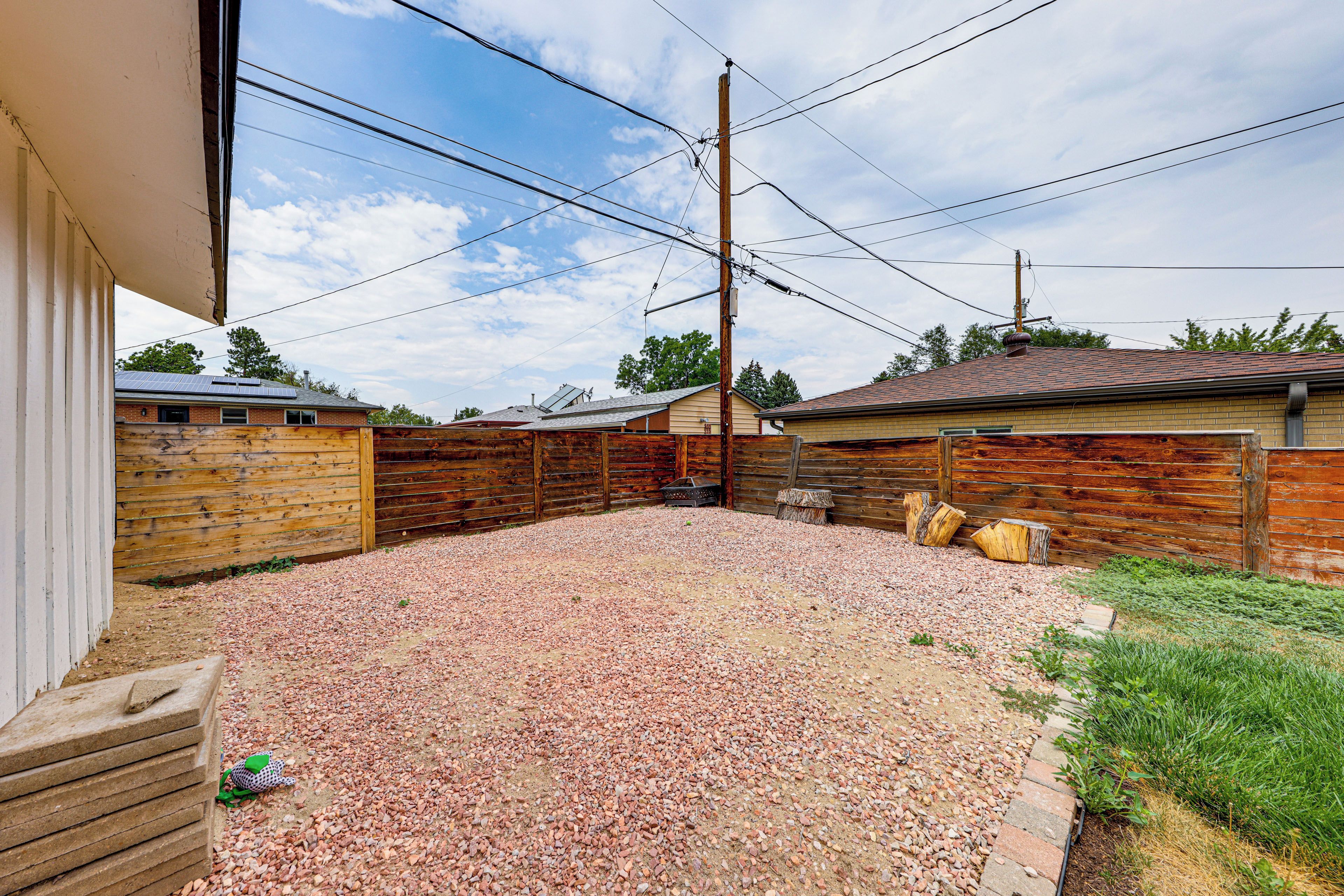 A backyard with a gravel surface, wooden fences, and utility poles.