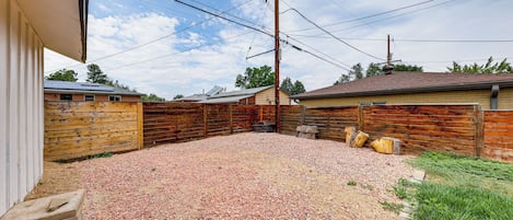 A backyard with a gravel surface, wooden fences, and utility poles.