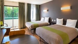 Ein Hotelzimmer mit zwei Betten, einem Schreibtisch und einem Stuhl.