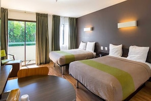 Habitación de hotel con dos camas, un escritorio y una silla.