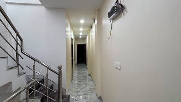 A hallway with a marble floor, a metal staircase, and a wall-mounted electrical box.