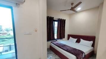 A bedroom with a bed, a ceiling fan, a window with curtains, and a view of the outside.