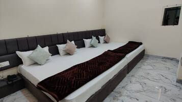 Quarto com cama, mesa de cabeceira, ventilador de teto, aparelho de ar condicionado e um pequeno espelho.