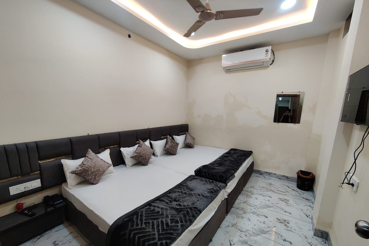 Quarto moderno com uma cama grande, ventilador de teto, ar condicionado e um pequeno espelho na parede.
