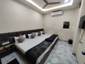 Quarto moderno com uma cama grande, ventilador de teto, ar condicionado e um pequeno espelho na parede.