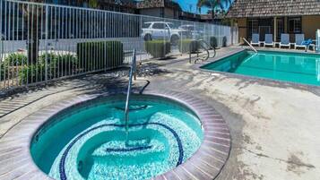 A swimming pool with a circular design, a water fountain, and a fenced area with lounge chairs.