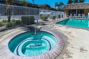 Una piscina con diseño circular, una fuente de agua y un área vallada con sillas de descanso.