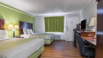Habitación de hotel con dos camas, un escritorio con silla, televisor y ventana con cortinas.