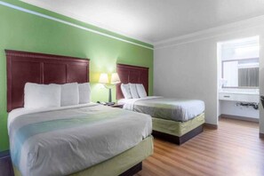 Habitación de hotel con dos camas, una mesita de noche, una lámpara y un ventanal.
