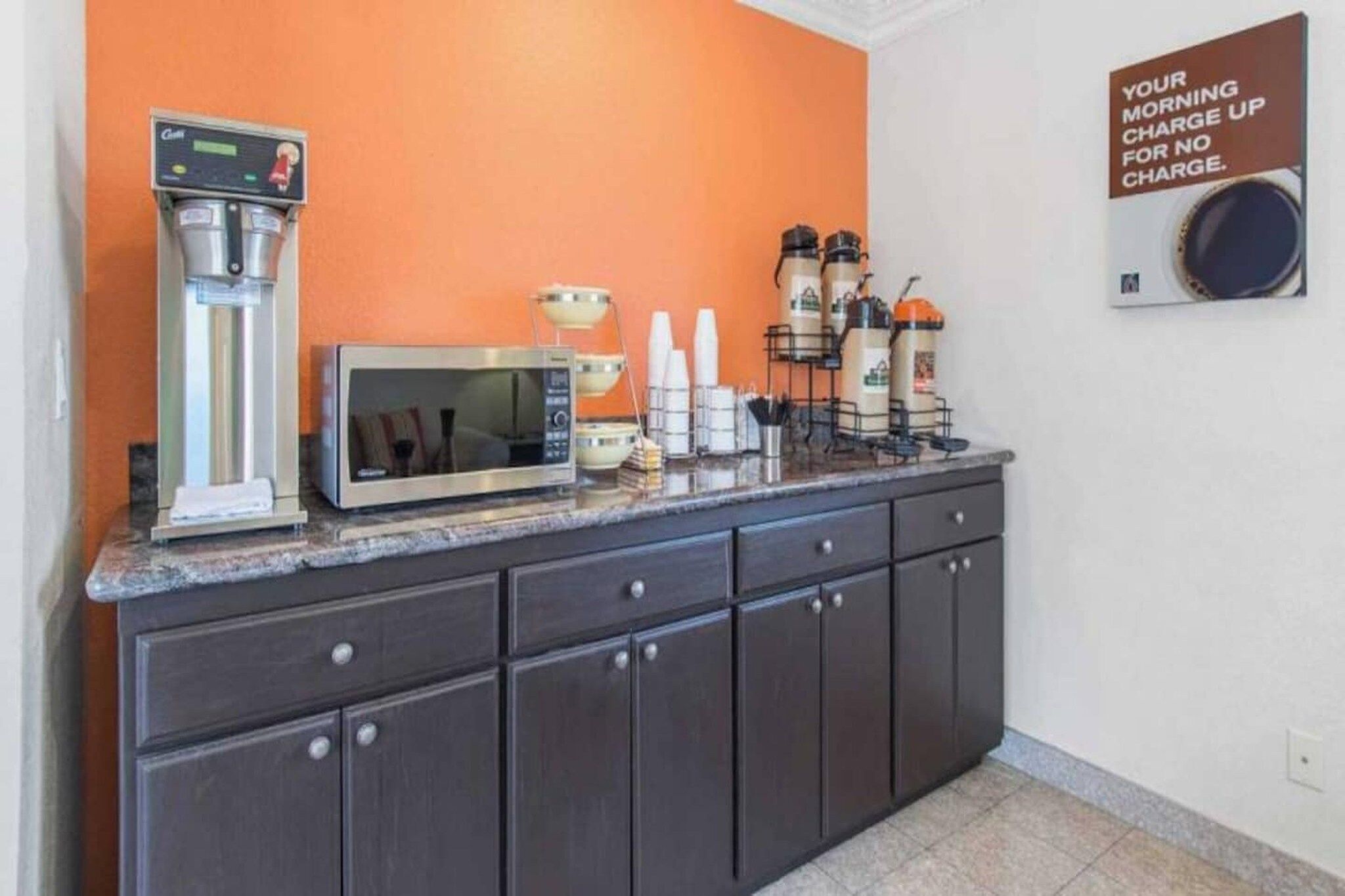 A kitchenette with a coffee machine, microwave, and beverage dispensers.