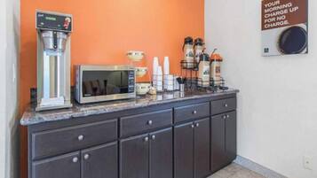 A kitchenette with a coffee machine, microwave, and beverage dispensers.