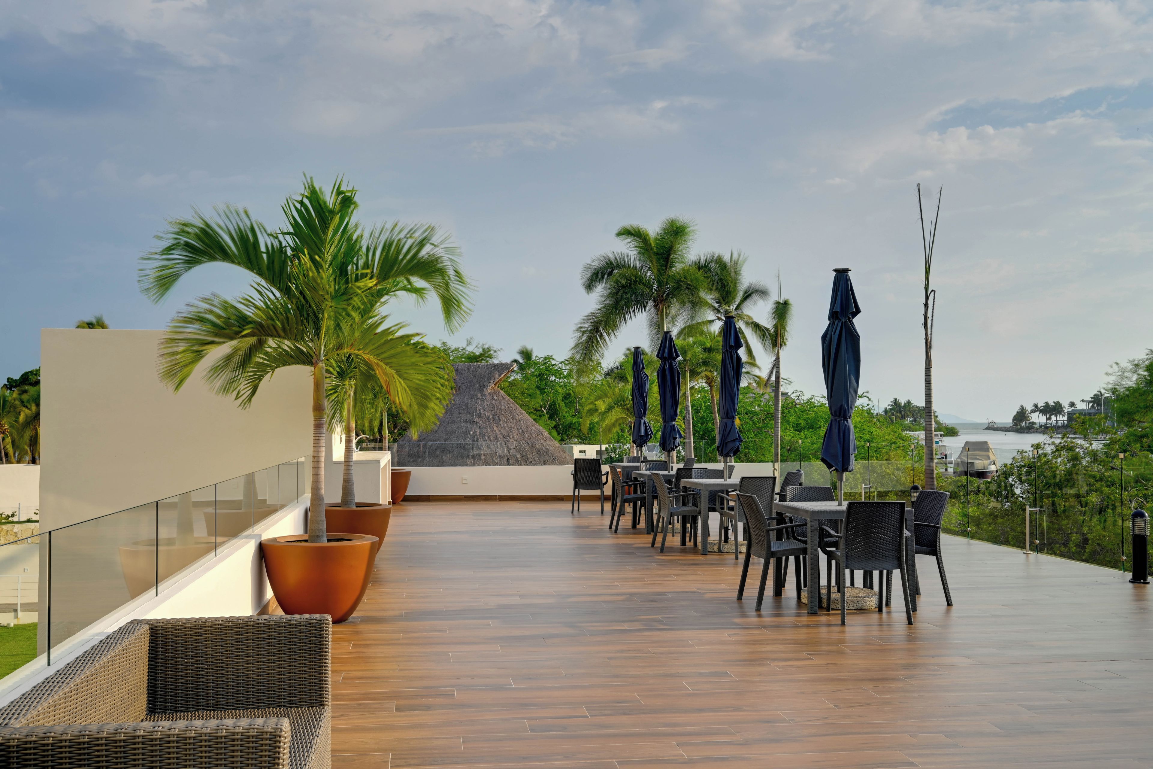 Terraza en la azotea con mobiliario exterior, palmeras y vistas al mar.
