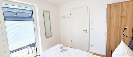 Una habitación de hotel con una cama, un armario de madera, un espejo y una puerta.