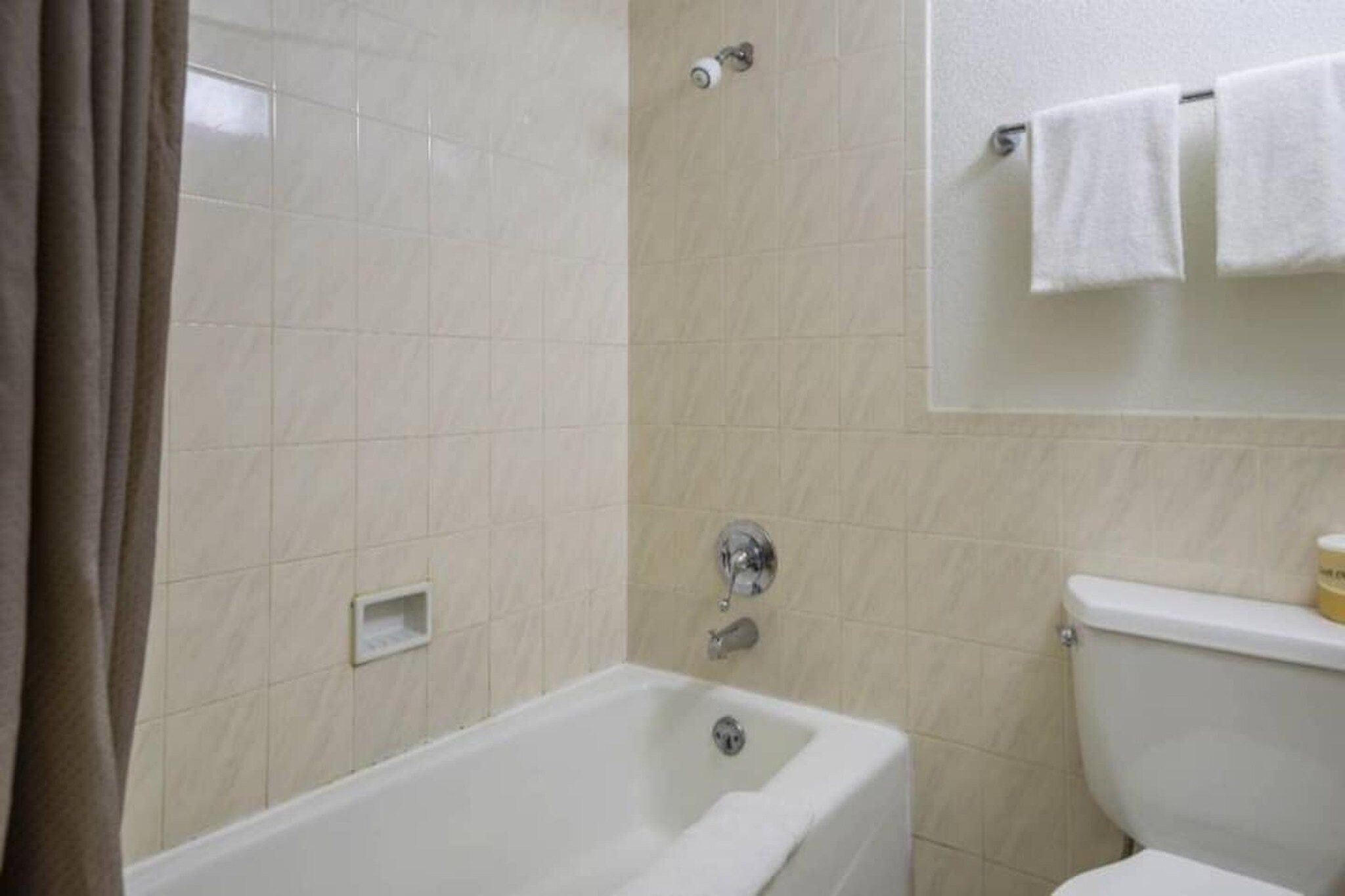 A bathroom with a bathtub, toilet, and shower area.