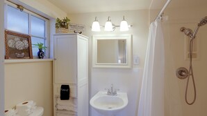 Een badkamer met toilet, wastafel, douche en een spiegel boven de wastafel.