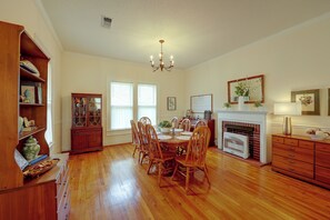 Un comedor amplio con mesa y sillas de madera, chimenea y estantería.