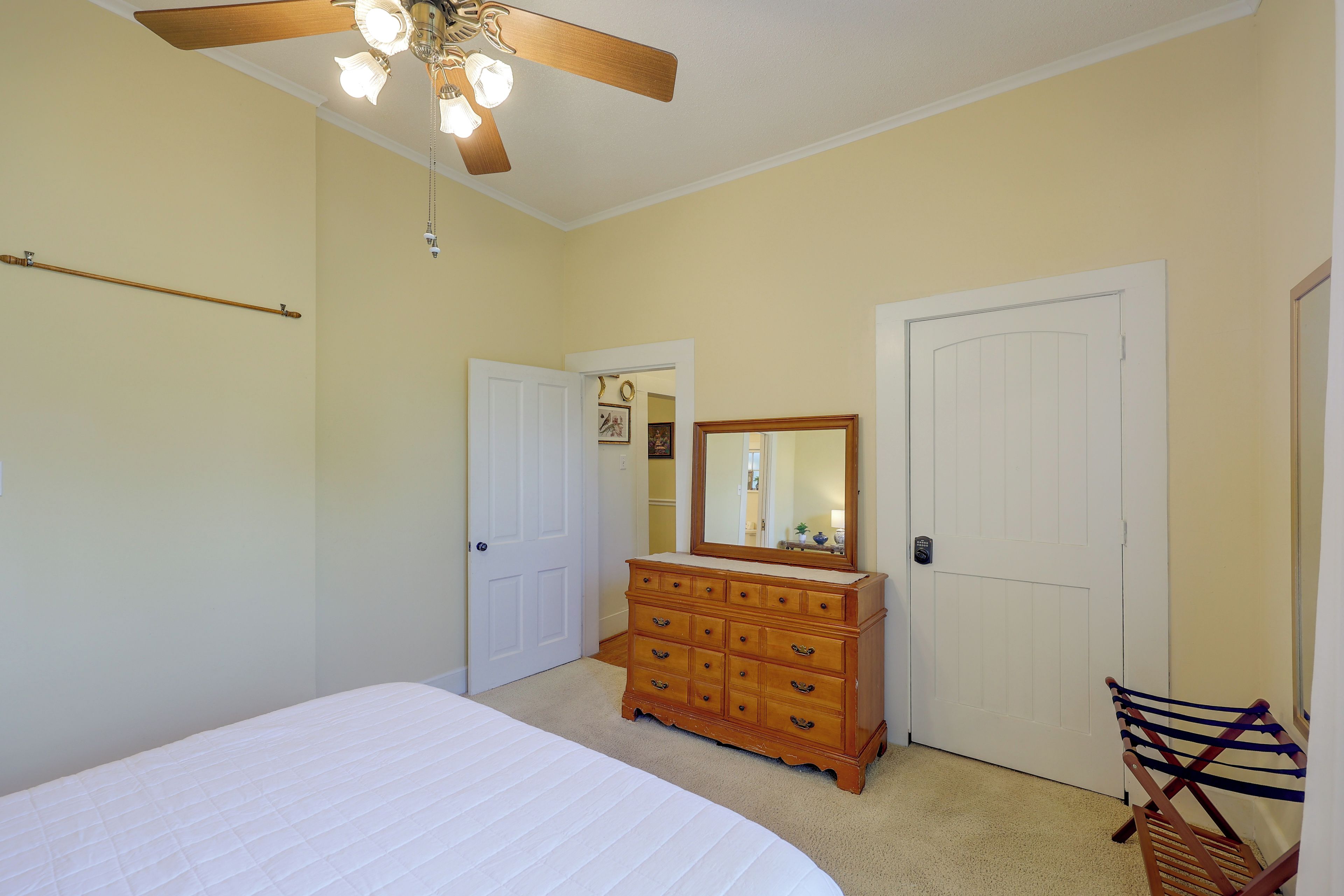 Un dormitorio con cama, cómoda y dos puertas.