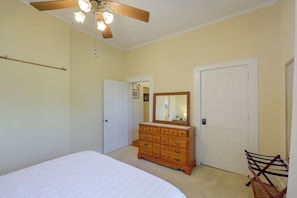 A bedroom with a bed, dresser, and two doors.