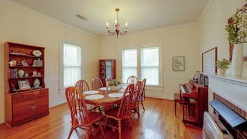 Un comedor con mesa de madera, sillas, una araña y un piano.