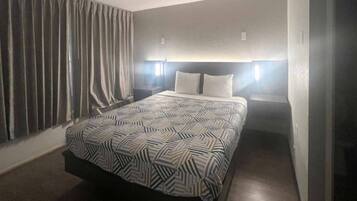 A hotel room with a bed, curtains, and bedside lamps.