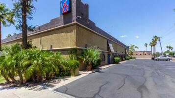 A motel with a prominent '6' sign, a parking lot, and palm trees.