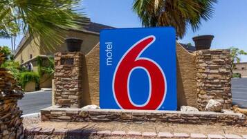 A motel sign with the number 6, surrounded by stone pillars and palm trees.