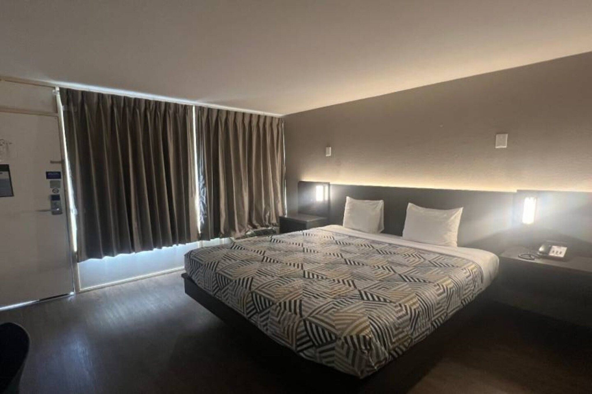 Een moderne hotelkamer met een groot bed, een bureau en een raam met gordijnen.