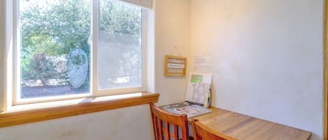 Une pièce avec une table en bois et une chaise, une fenêtre avec des stores et un calendrier accroché au mur.