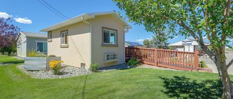 A single-story house with a small front yard, a wooden fence, and a tree.