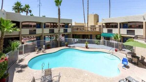 A swimming pool with a curved edge, surrounded by a fence, and adjacent to a building with multiple balconies. - 2 Full Beds|NS| Micfridge (Glendale)