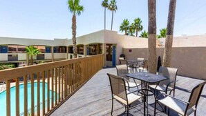 A poolside area with a wooden deck, outdoor seating, and a view of a building with multiple windows. - 2 Full Beds|NS| Micfridge (Glendale)