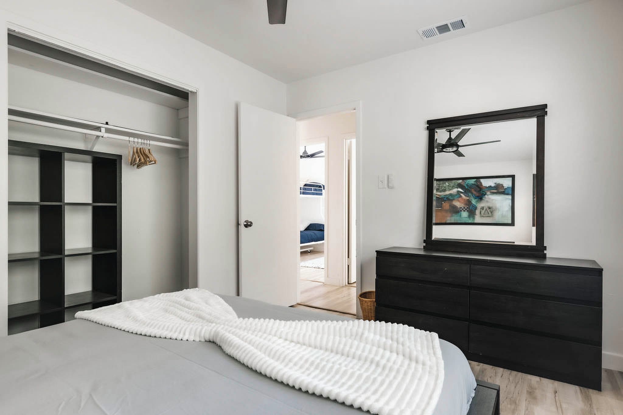 A bedroom with a bed, a wardrobe, a dresser, and a door leading to a bathroom.