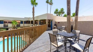 A poolside area with a wooden deck, outdoor seating, and a view of a building with multiple windows. - 2 Full Beds | Mobil Access Tub Nsmk Micfridg (Glendale)