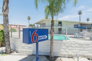 A motel sign with a pool area in the background.