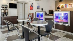 Un moderno vestíbulo de hotel con mostrador de recepción, zona de estar y máquinas de café.