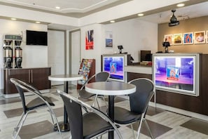 Um hall de hotel moderno, com balcão de recepção, área de estar e máquinas de café.