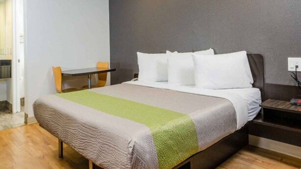 Una habitación de hotel con una cama, una mesita, una silla y una mesita de noche.