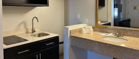 A modern bathroom with a sink, mirror, and countertop.