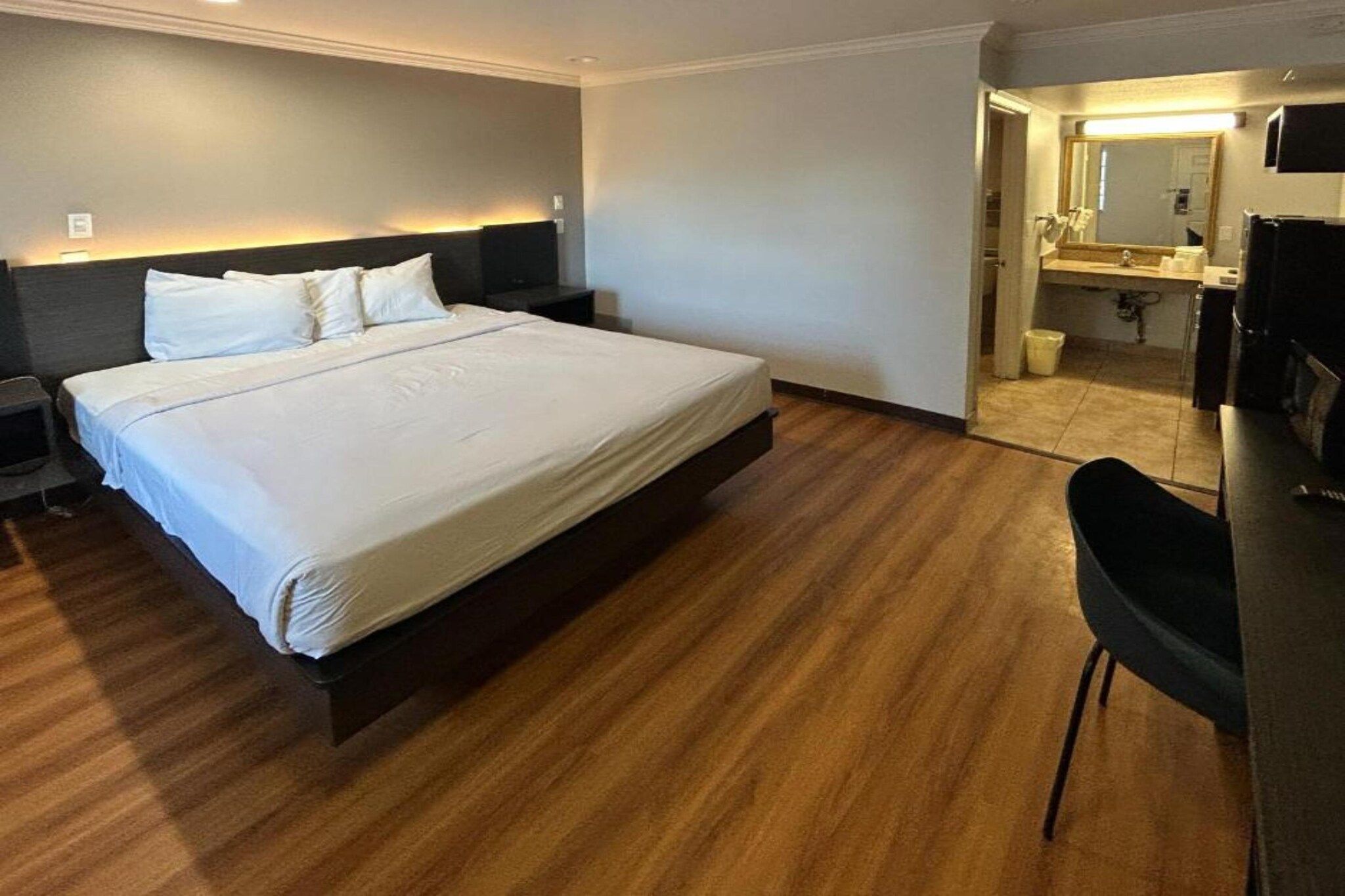Habitación de hotel con una cama grande, un escritorio y un baño visible a través de una puerta abierta.