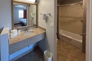 Un baño con lavamanos, espejo y ducha.