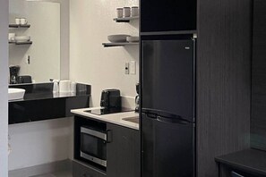 A modern kitchen with a built-in oven, a refrigerator, and a coffee maker.