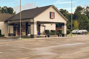 A standalone motel with a single-story structure, a covered parking area, and a visible sign with the number 6.