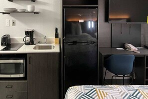 A compact kitchenette with a microwave, toaster, coffee maker, and a sink.