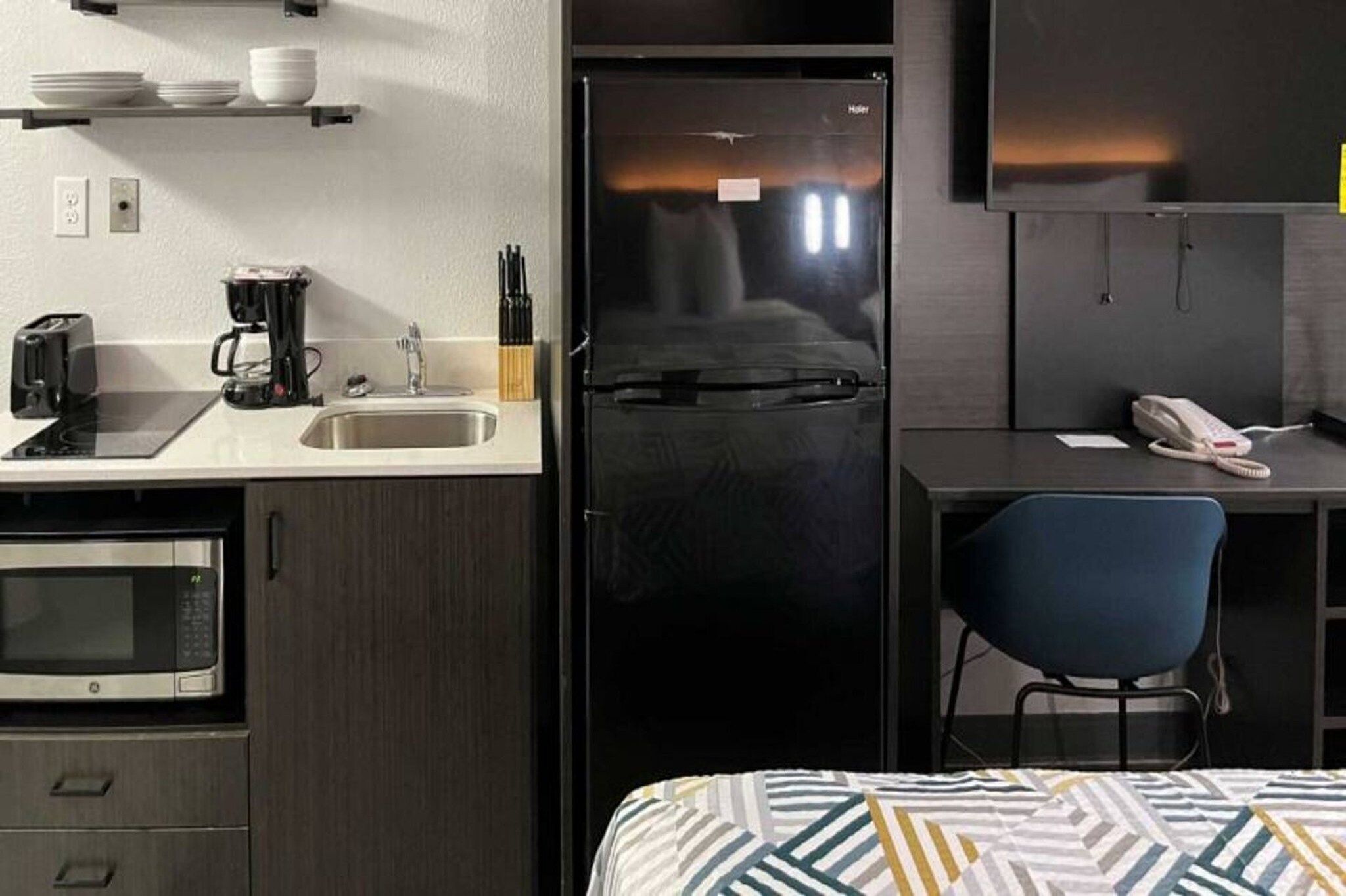 Uma cozinha compacta equipada com micro-ondas, torradeira, cafeteira e pia.