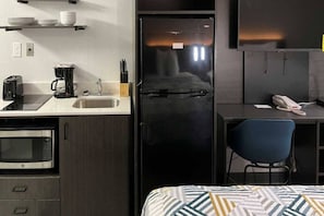 A compact kitchenette with a microwave, toaster, coffee maker, and a sink.
